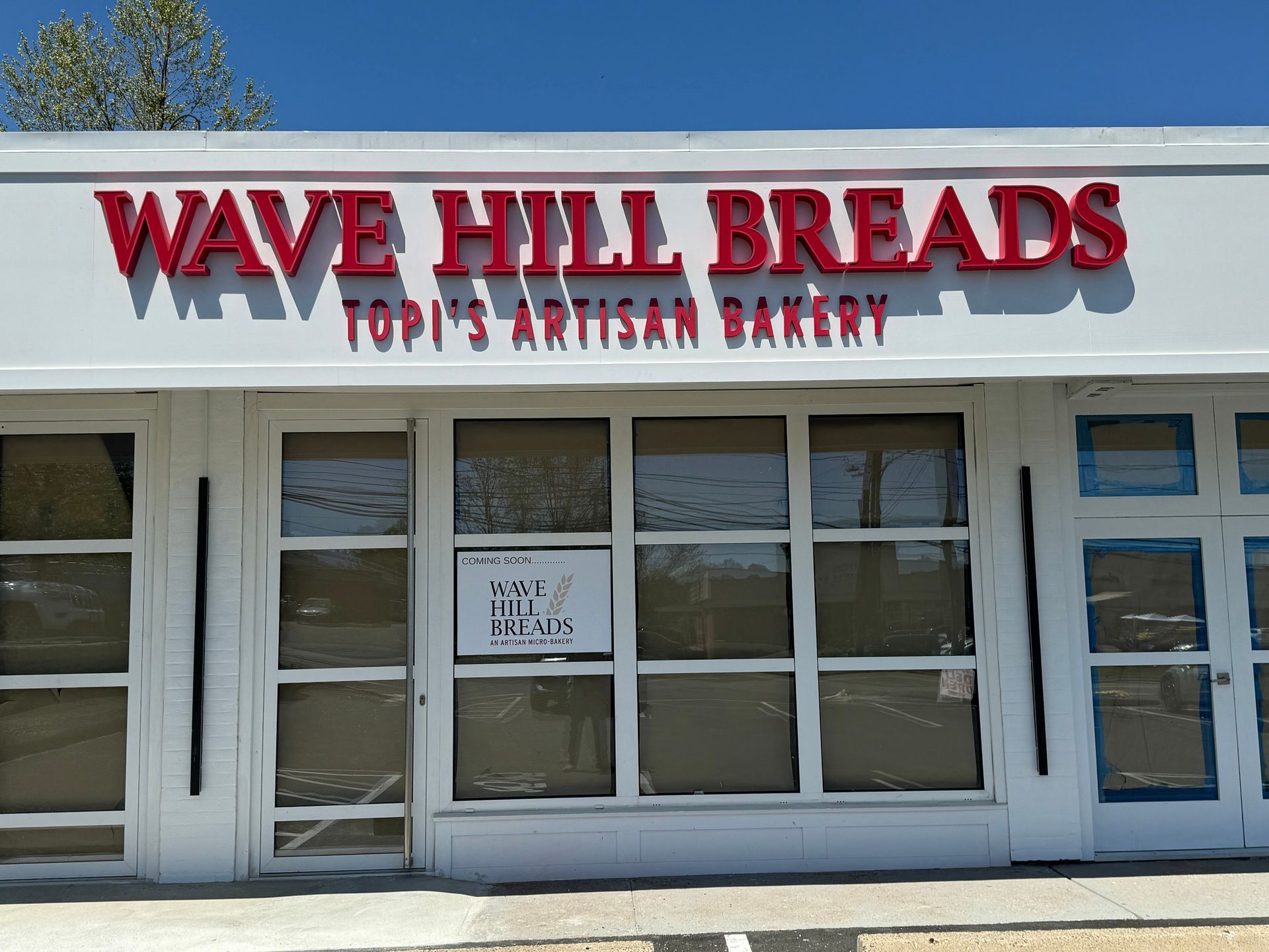A white building with a red sign that says wave hill breads