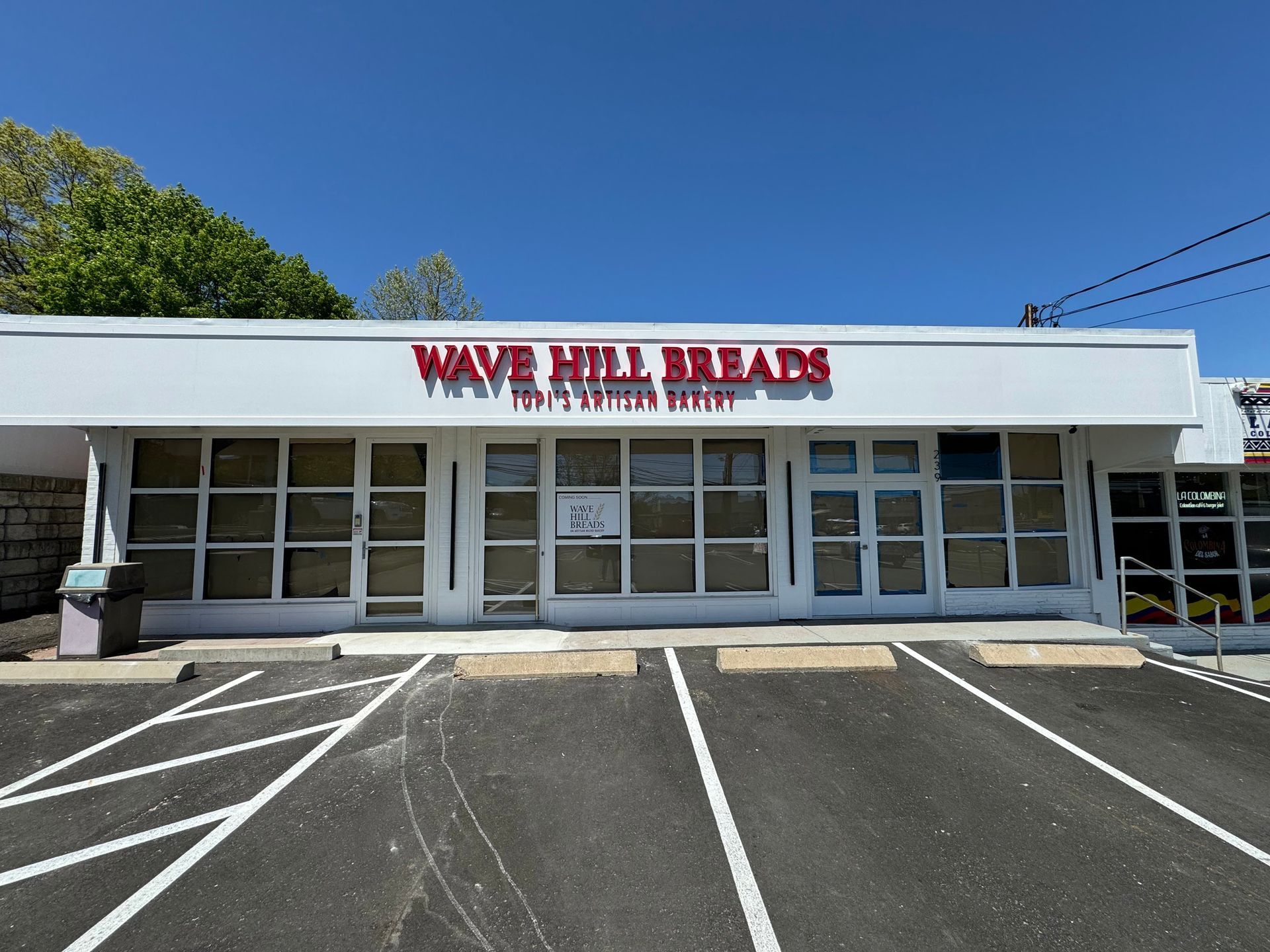 A white building with a red sign that says wave hill breads