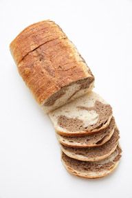 A loaf of bread is sliced into slices on a white surface.