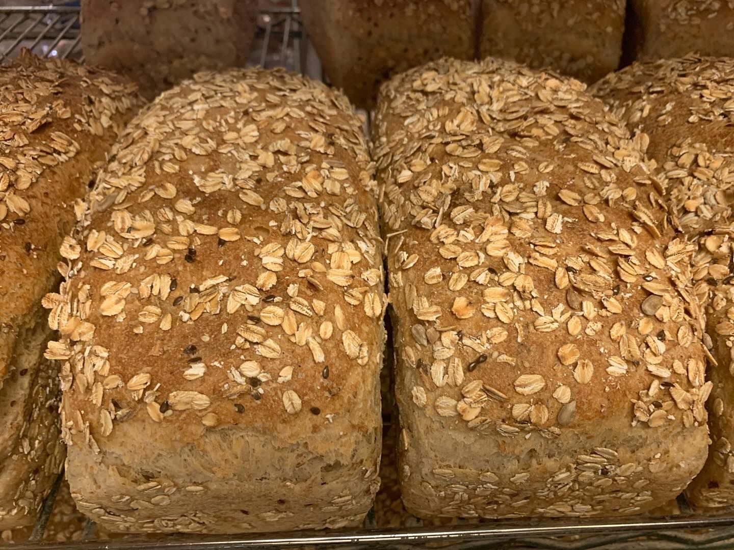 A loaf of bread with oats on it is sitting on a rack.