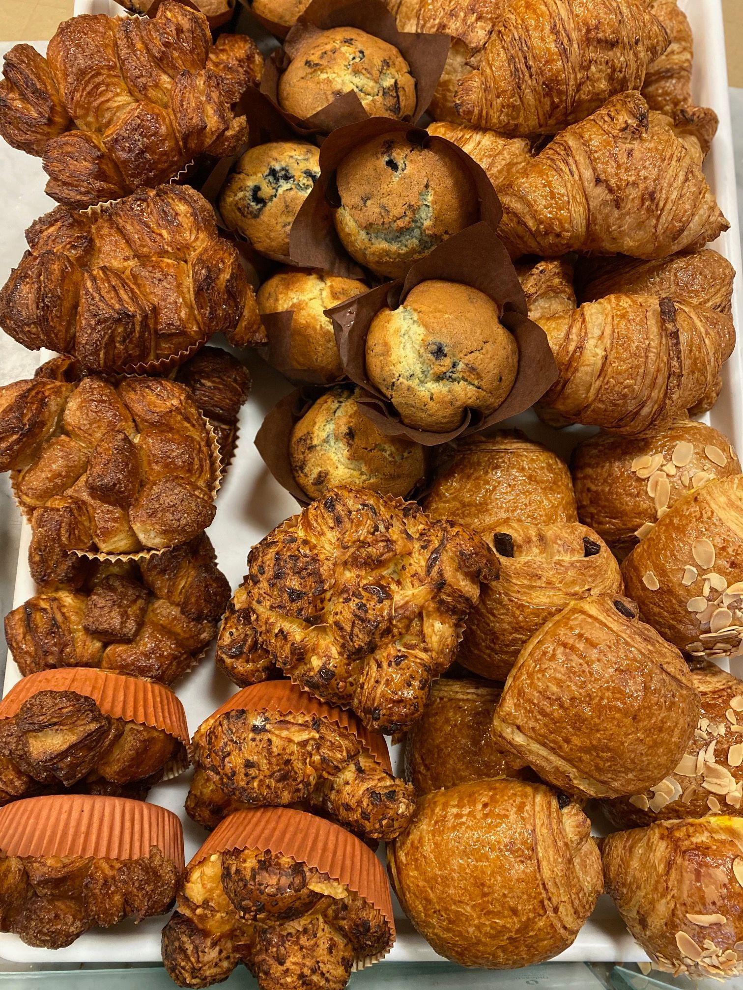 A tray of pastries including muffins and croissants