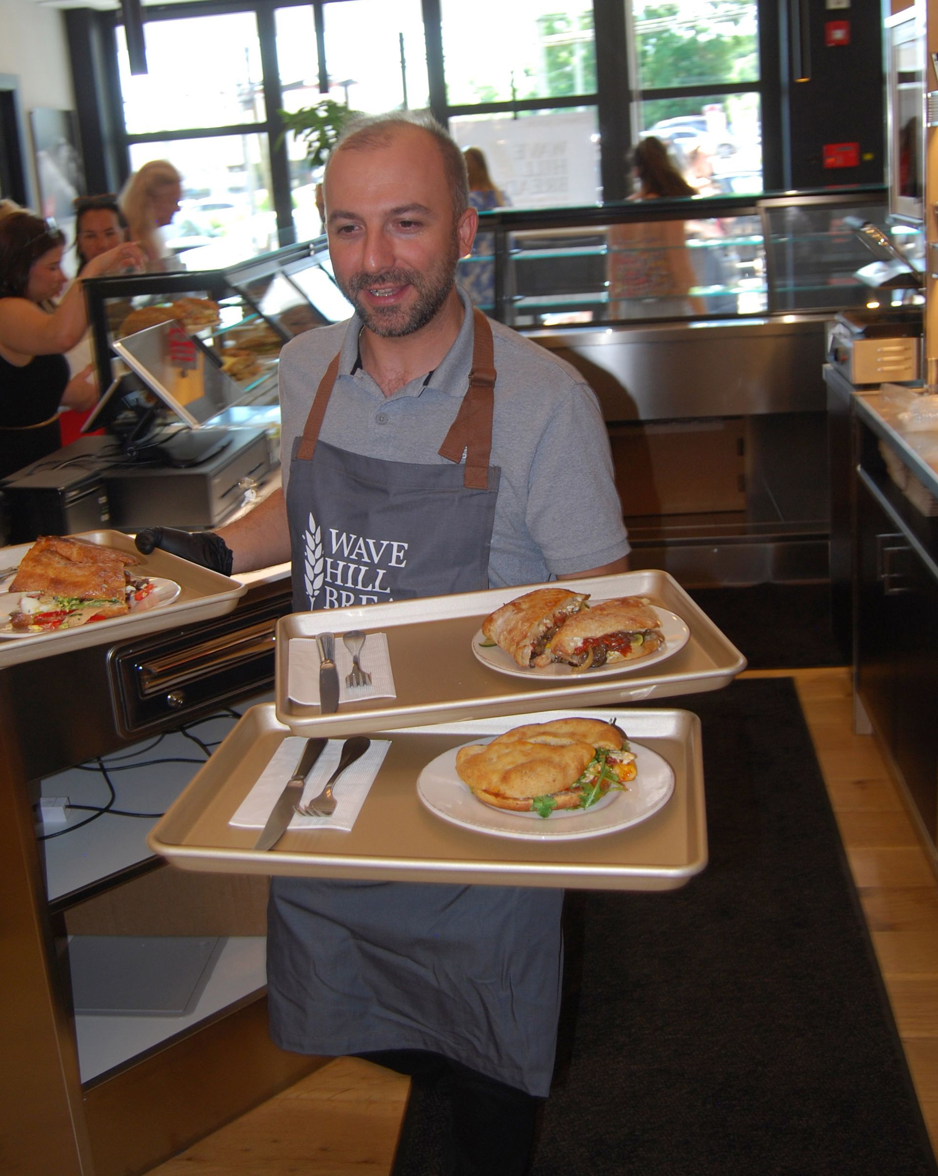 A man in an apron is holding two trays of food