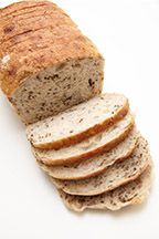 A loaf of bread is sliced on a white surface.