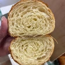 A person is holding a slice of croissant in their hand.