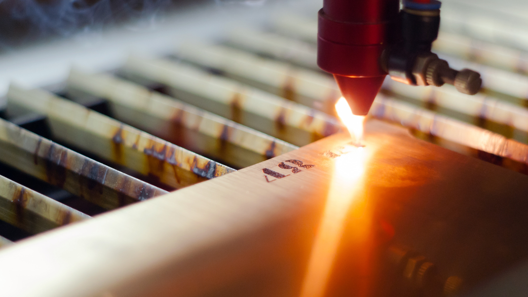 A close up of a laser cutting machine cutting a piece of metal.