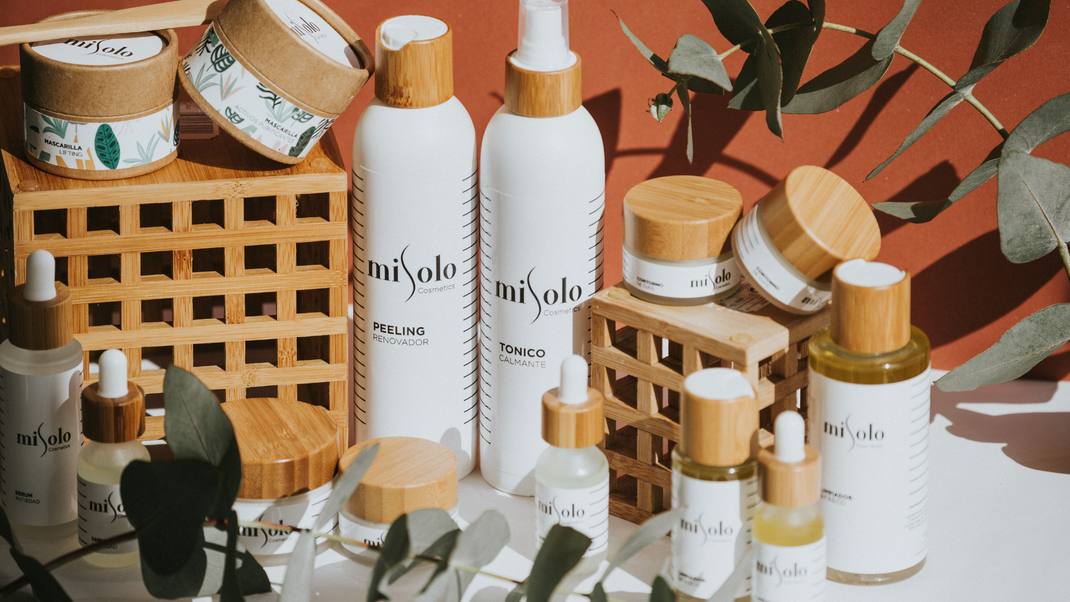 A variety of bottles and jars of cosmetics are sitting on a table.