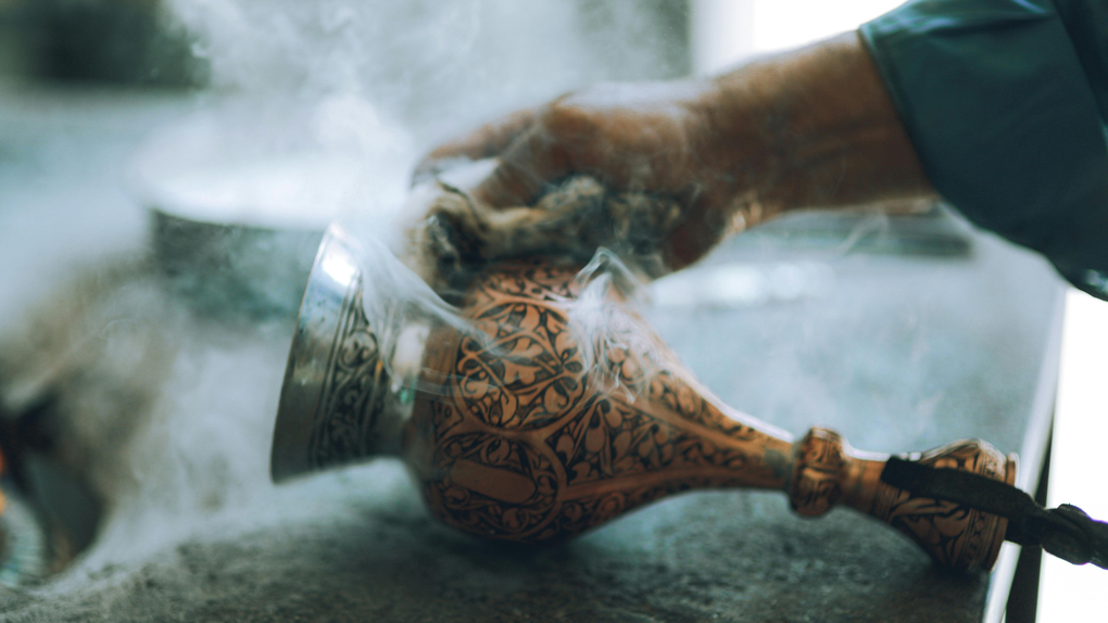 A person is pouring water from a pitcher into a glass.