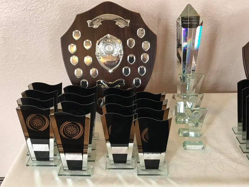 Club crest with engraved panels and sports trophies on table