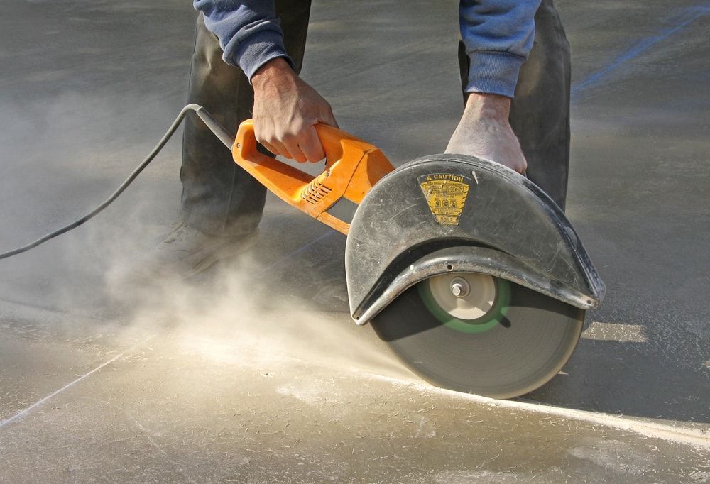 A gardener in a protective overall sprays fruit trees with a long sprayer in an orchard.