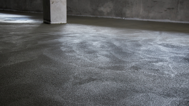 Empty concrete parking garage floor with wet, reflective surface and a support column