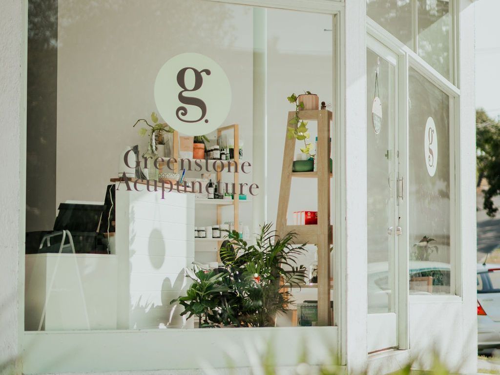 A store front with a sign on the window that says `` greenstone acupuncture ''.