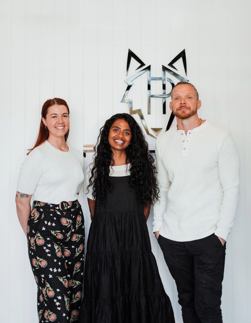 Three people are standing next to each other in front of a wall.