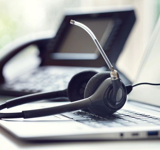 Headset on a laptop keyboard near a telephone; office setup.