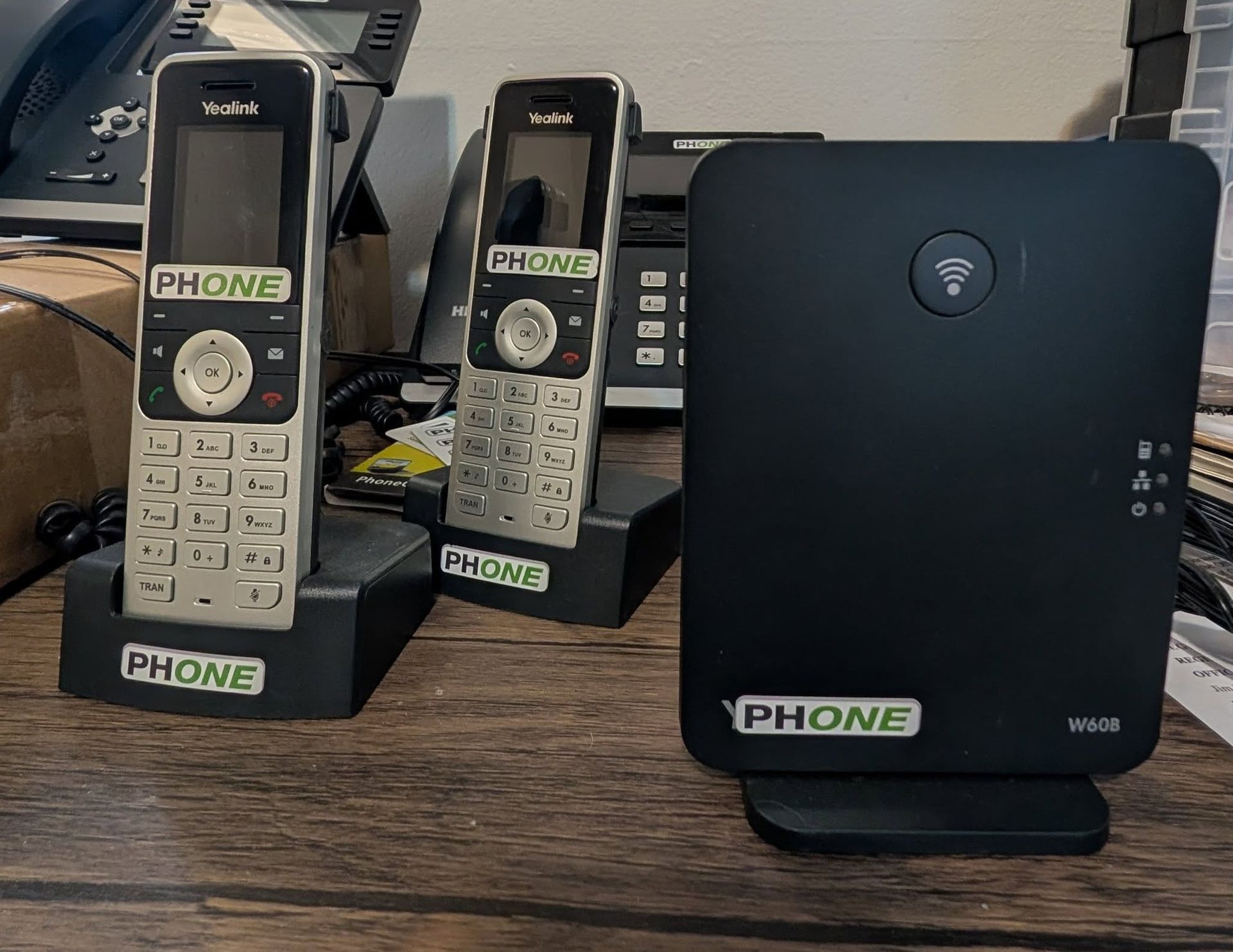 Two cordless phones and a base station on a desk, all with 