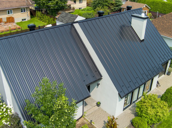 Toiture métallique gris foncé sur une maison à deux étages avec façade blanche et cheminée.