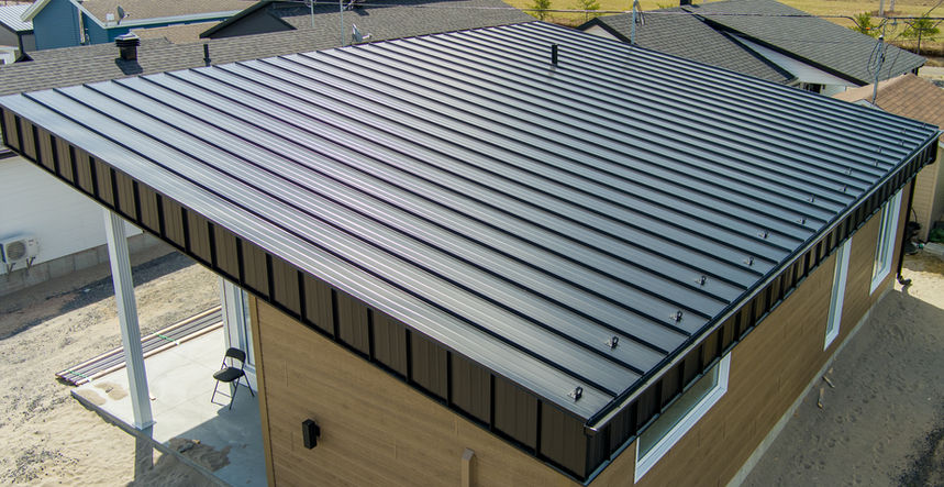 Toiture métallique noire sur un bâtiment beige avec des finitions blanches ; vue extérieure.