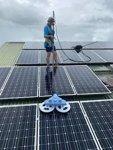 A Man is Standing on Top of a Roof Next to a Boat — Pain in the Glass Window Cleaning in Cannonvale, QLD