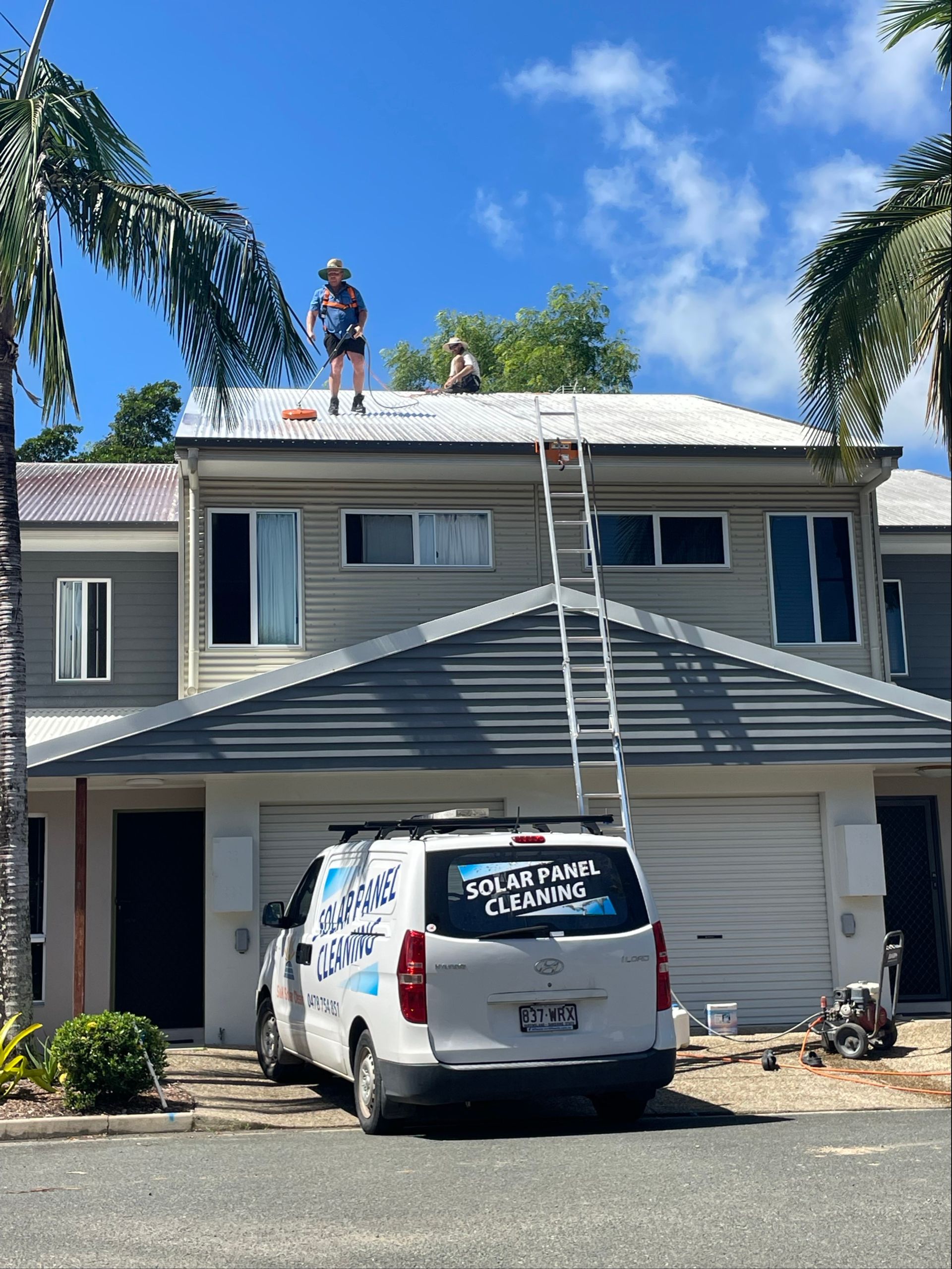 A Man is Standing on Top of a Roof Next to a Boat — Pain in the Glass Window Cleaning in Cannonvale, QLD