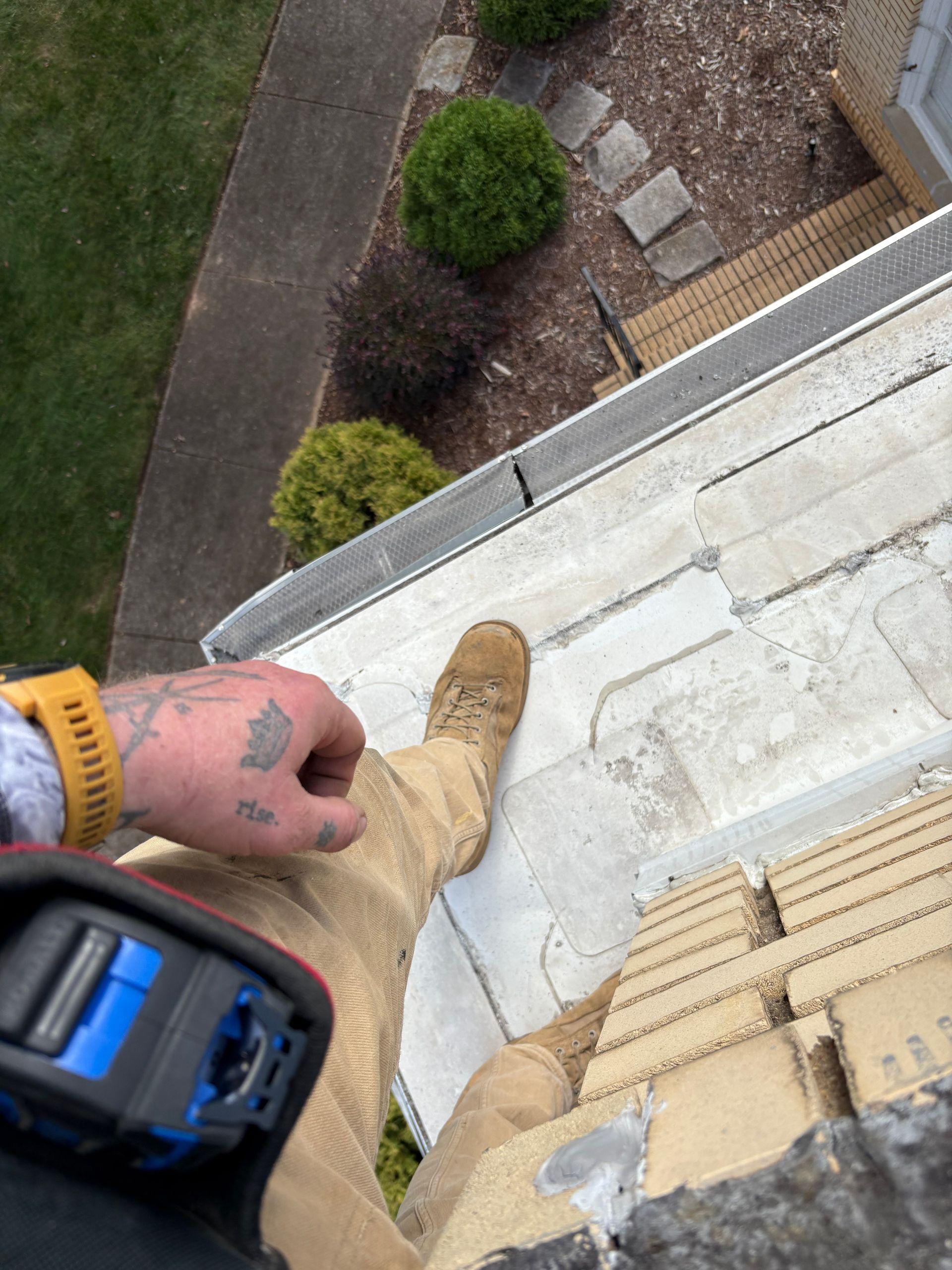 Person kneeling, cutting black trim on white panel outdoors.