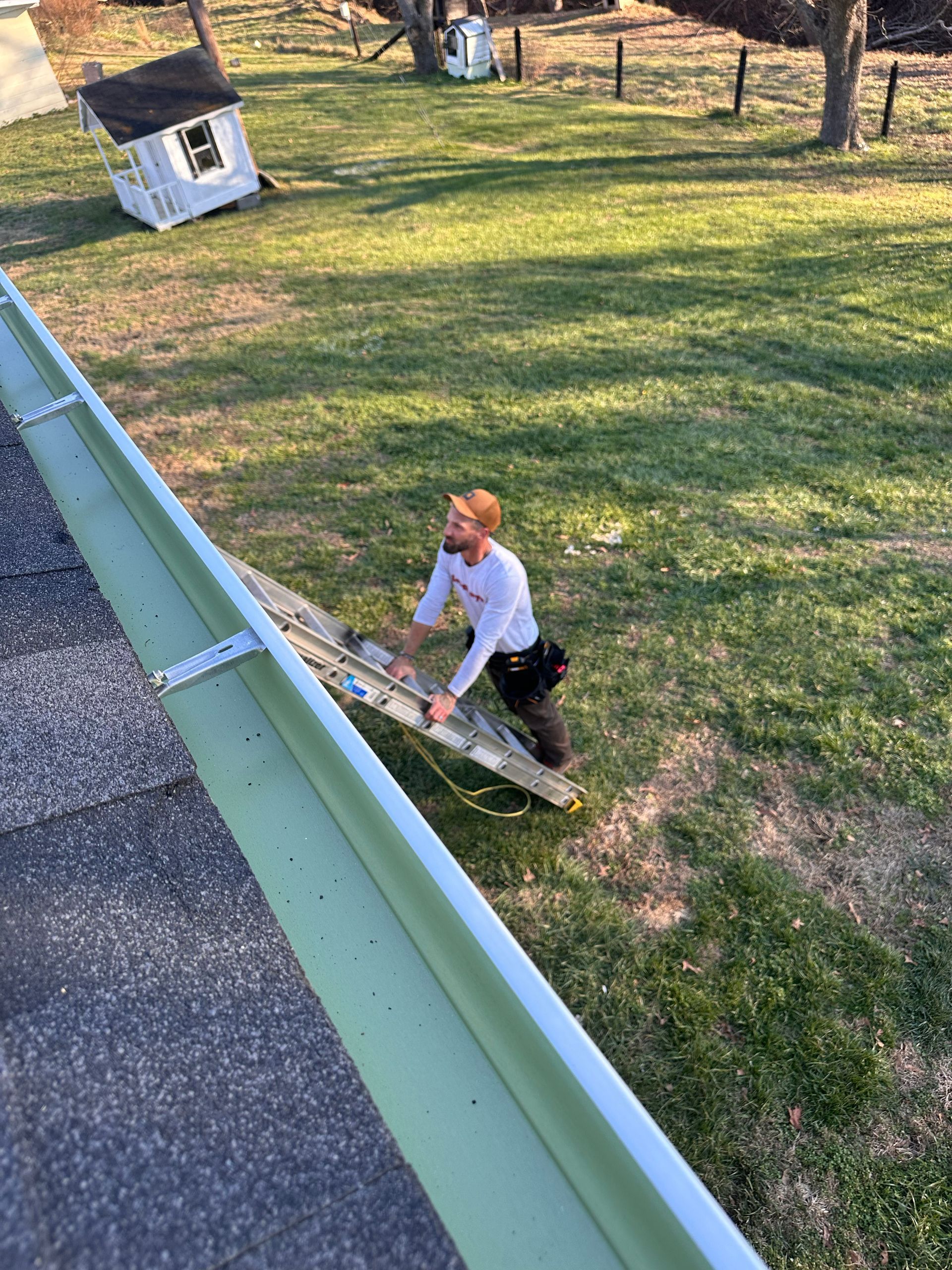 Two roofers installing asphalt shingles on a roof; one-half covered, with vents.
