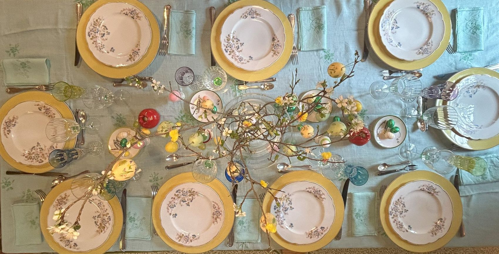 Easter table setting with floral plates, yellow chargers, and spring decorations.