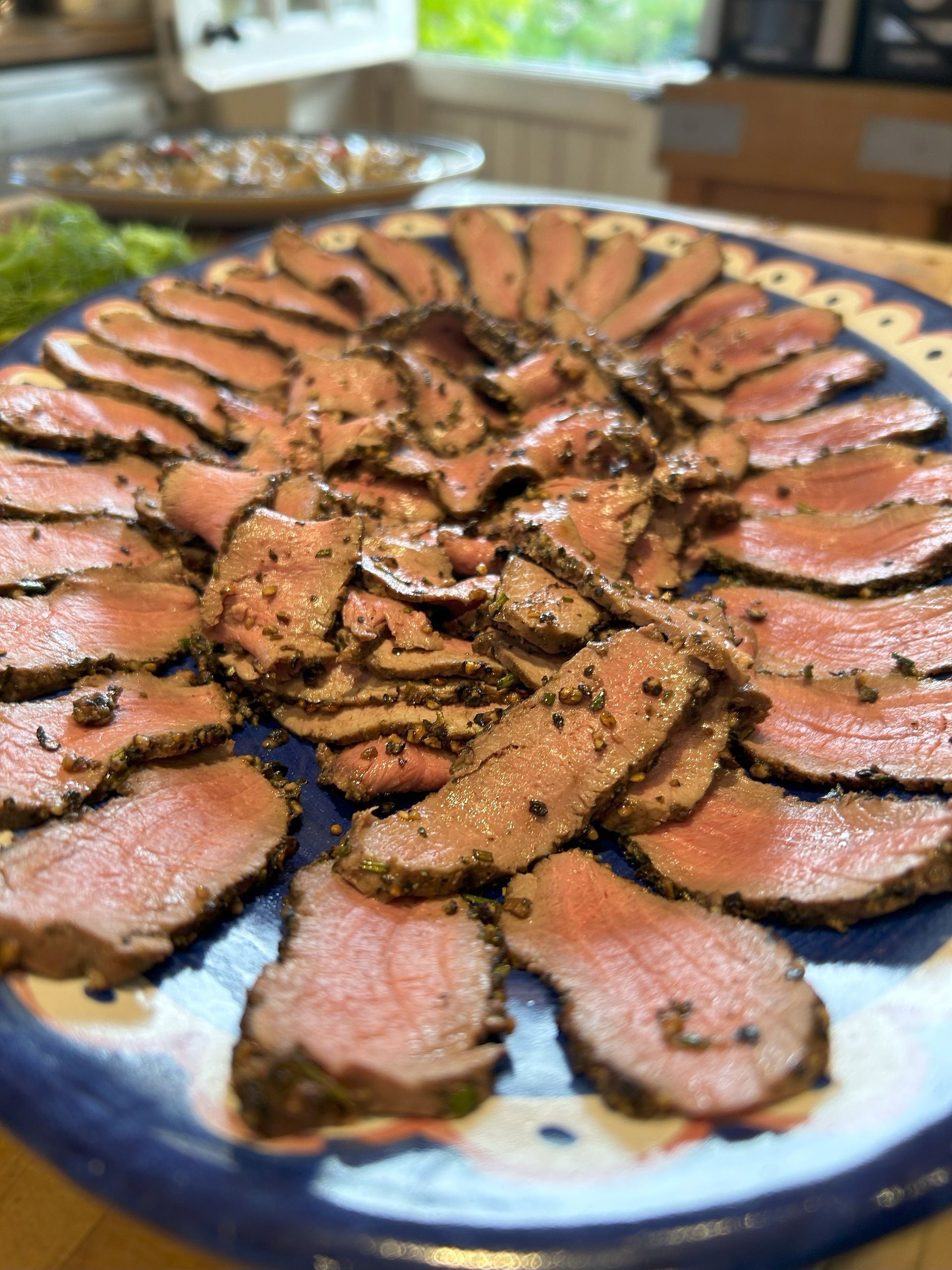 Sliced roast beef arranged on a decorative blue and white plate, ready to serve.