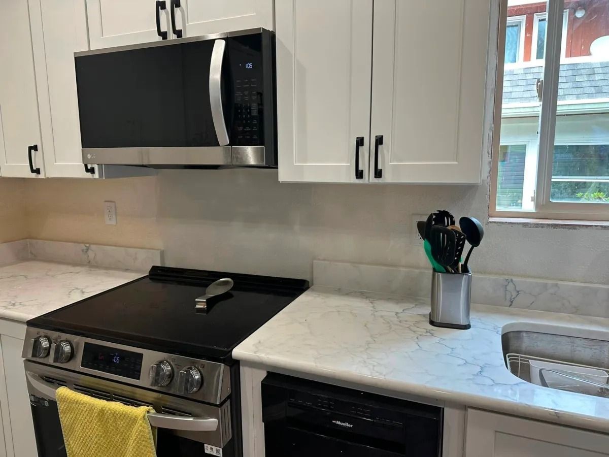 Kitchen with white cabinets, stainless steel appliances, and a countertop with gray veining.