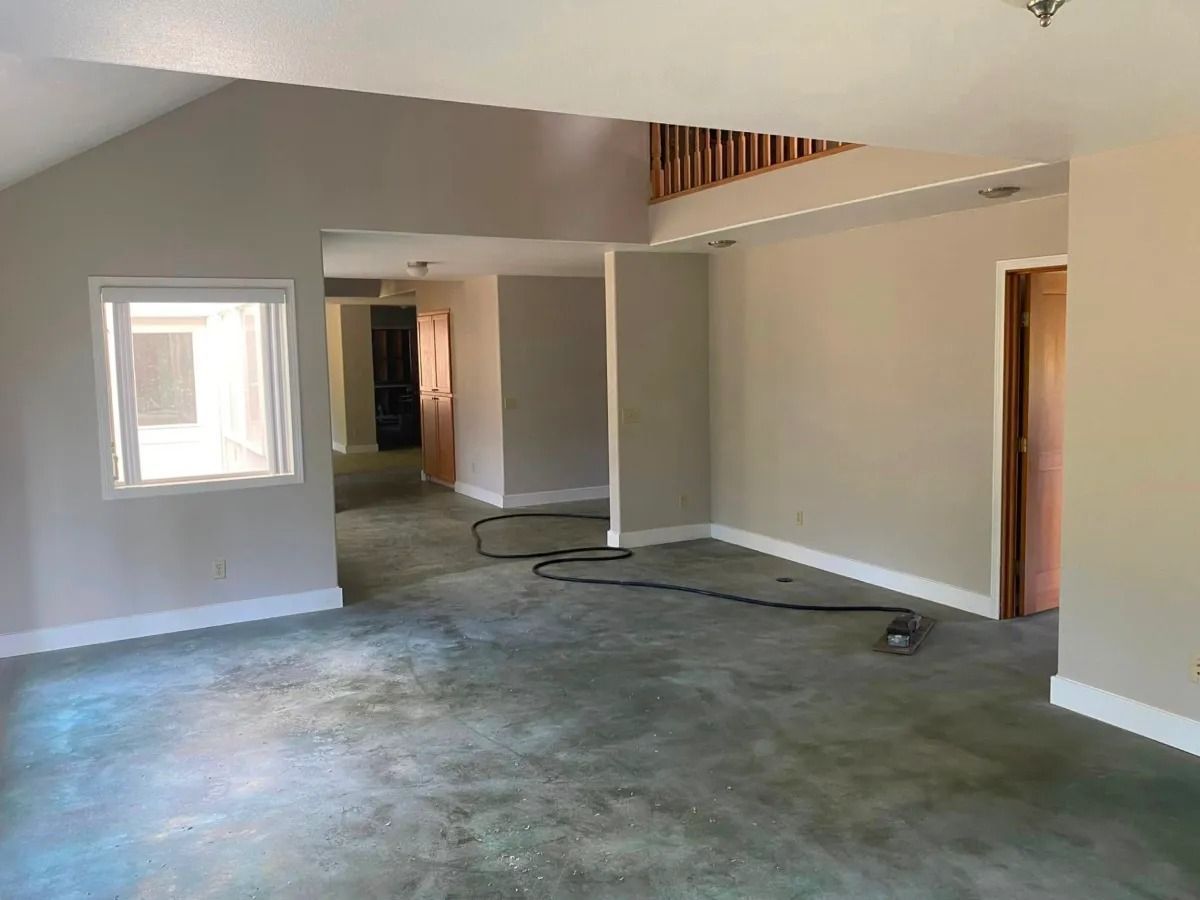 Empty room with green carpet, light walls, and open doorways to other rooms.