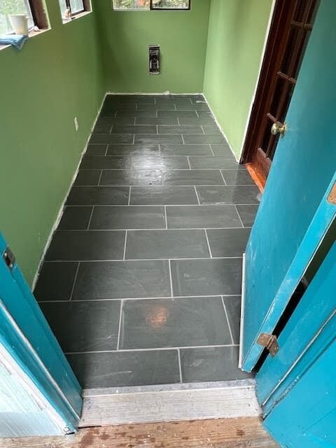 Dark tiled floor in a room with green walls. A blue doorway is at the entrance.