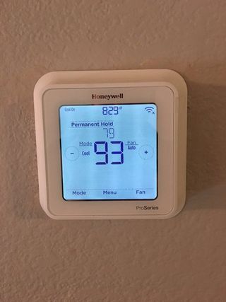 Honeywell thermostat displaying 77 degrees, set to 93 degrees, with