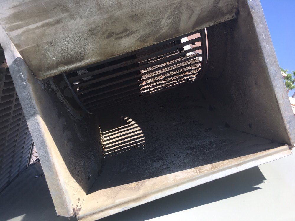 Inside of a rectangular air vent on a roof. Metal bars and walls are visible, lit by sunlight.