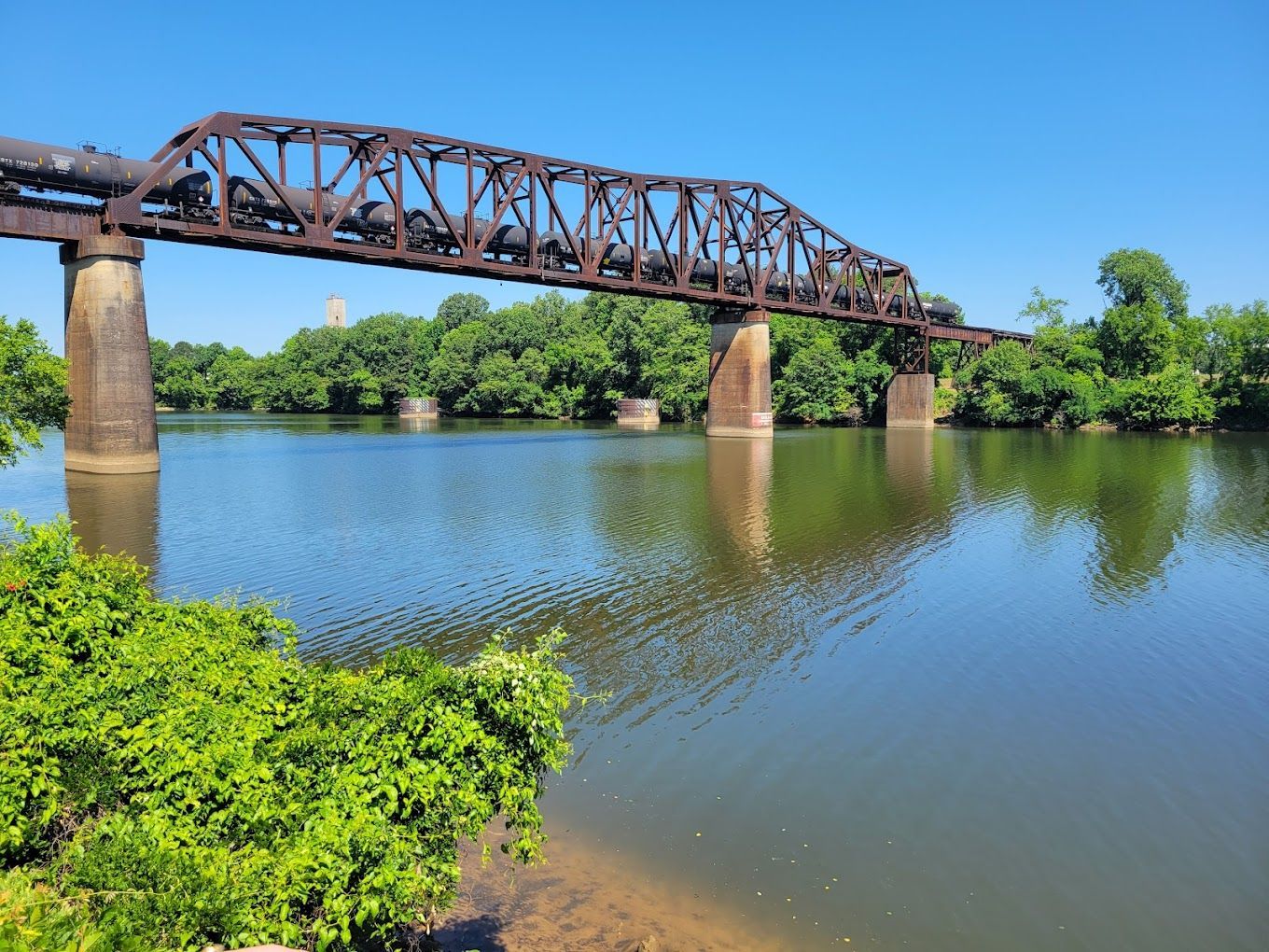 classic train bridge spans the Black Warrior River at sunset.