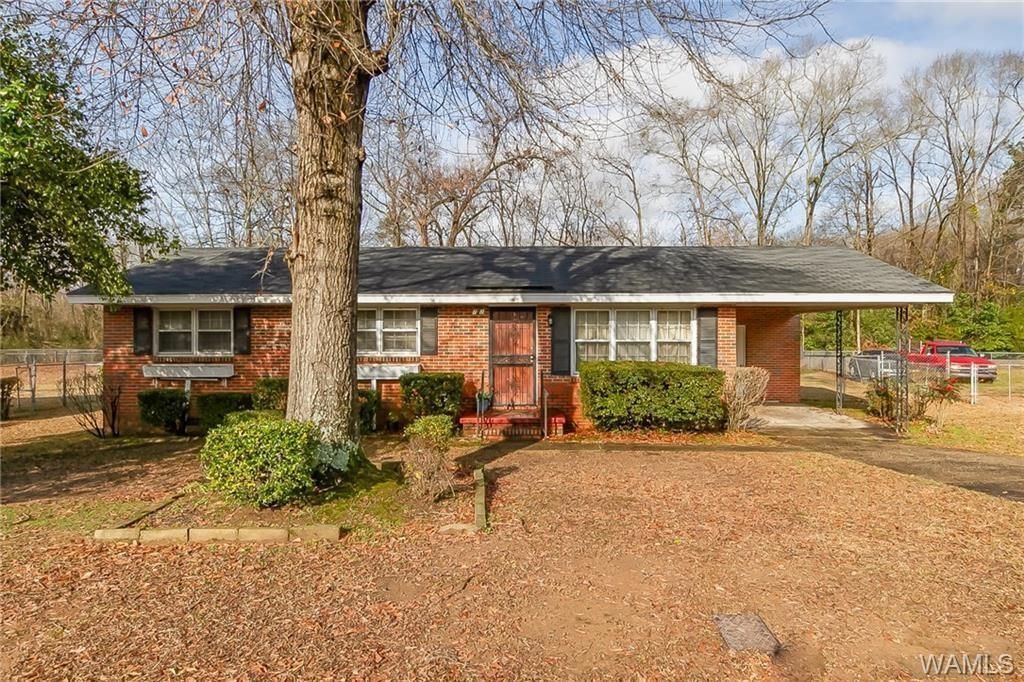 Single-family home with a rustic exterior and a tree