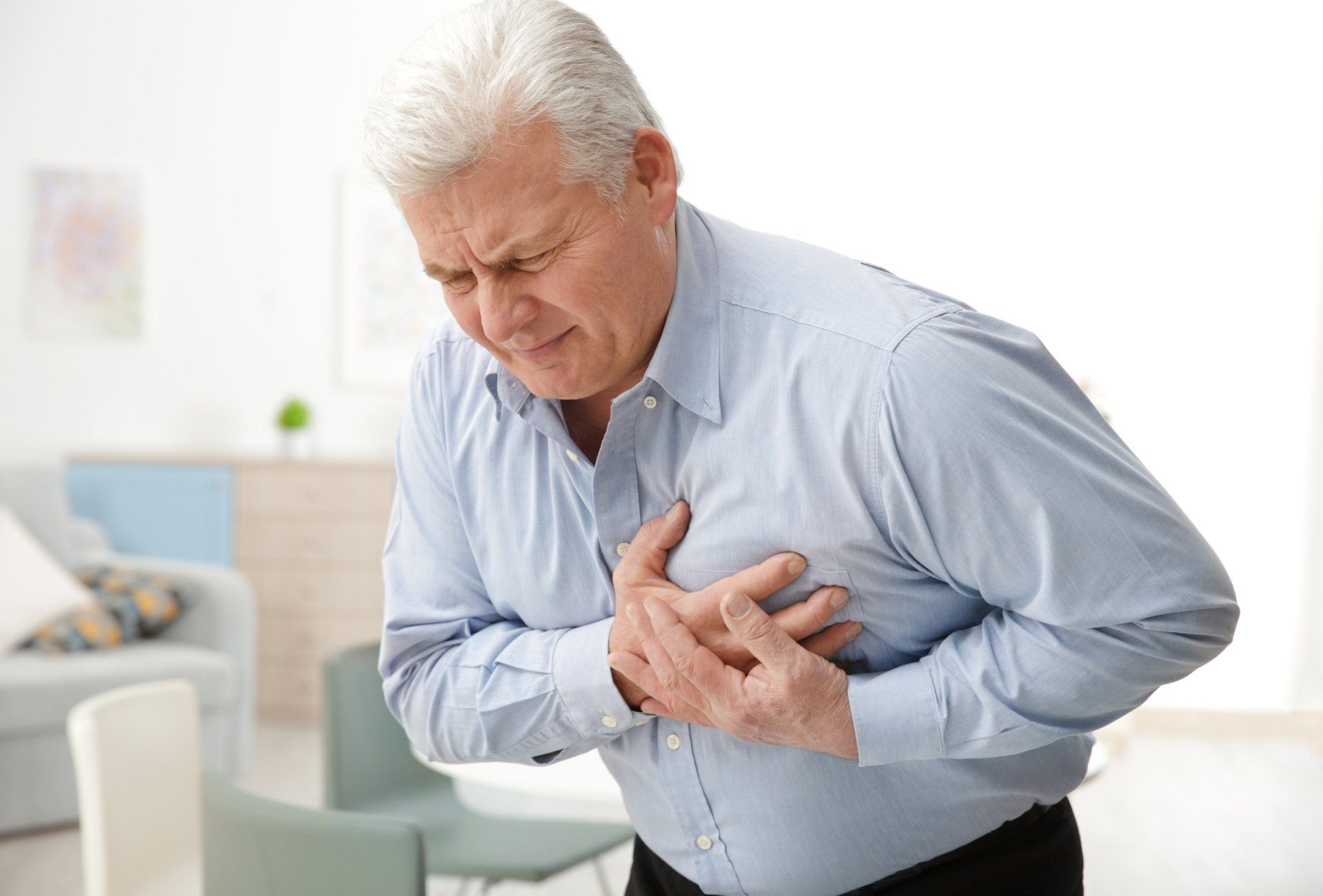 An elderly man is holding his chest in pain.