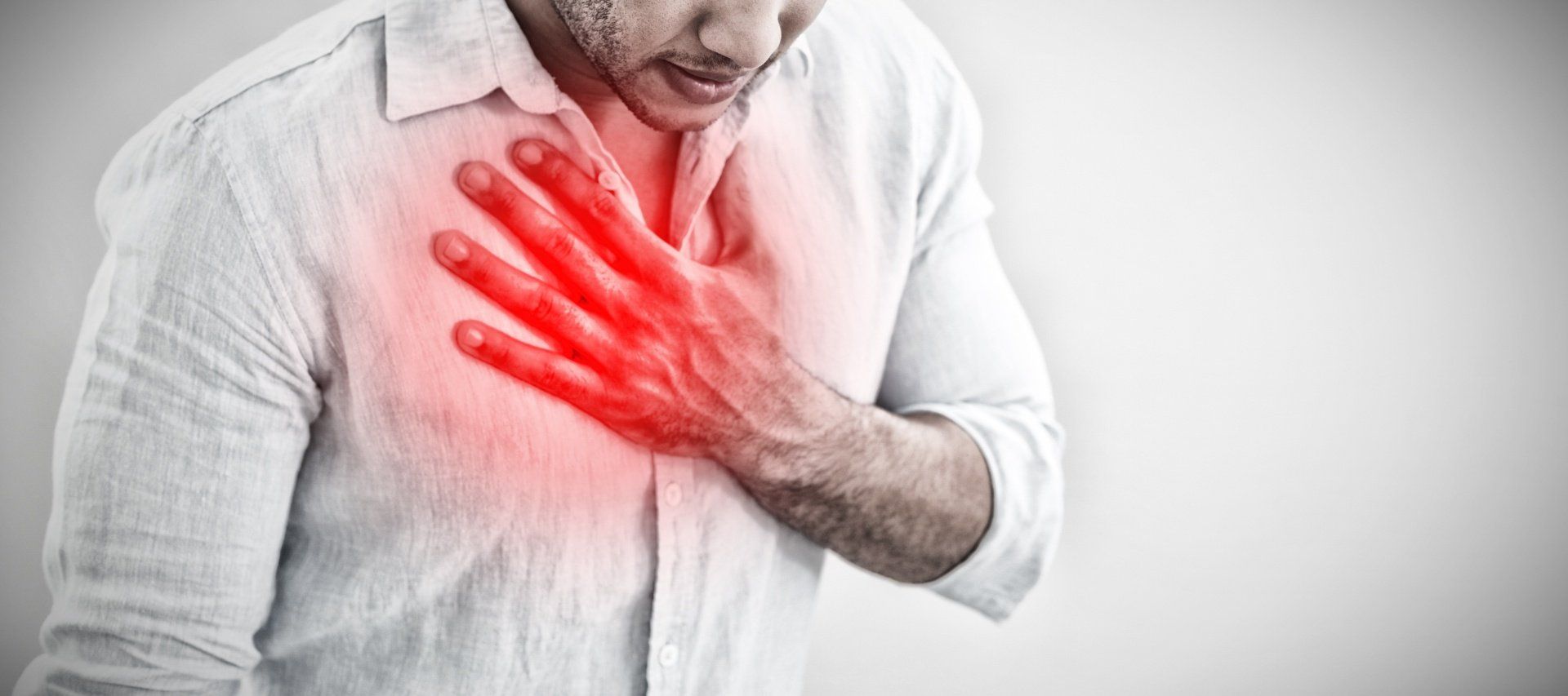 A man is holding his chest in pain because he has a heart attack.