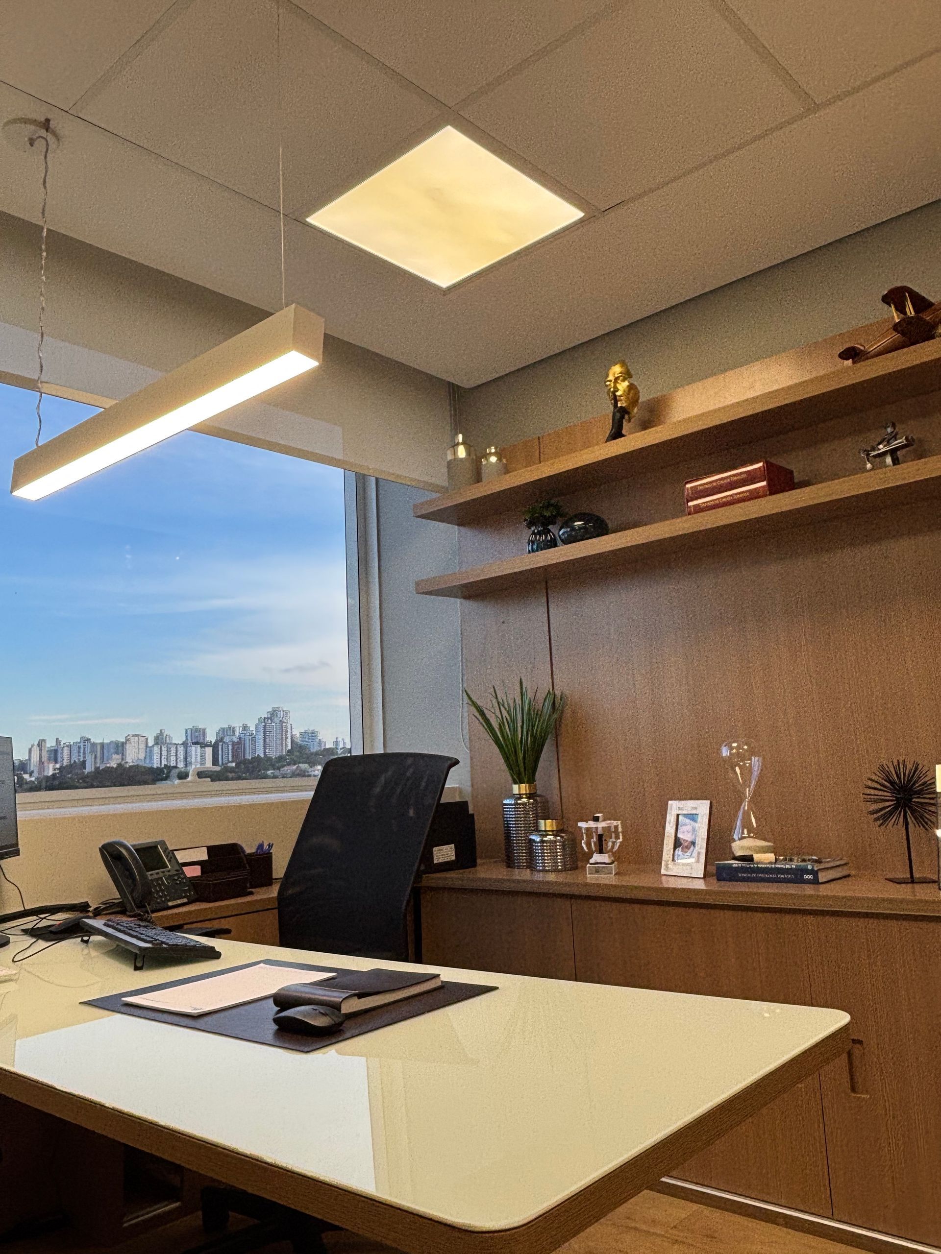 Uma mesa com um computador em um escritório com vista para a cidade.