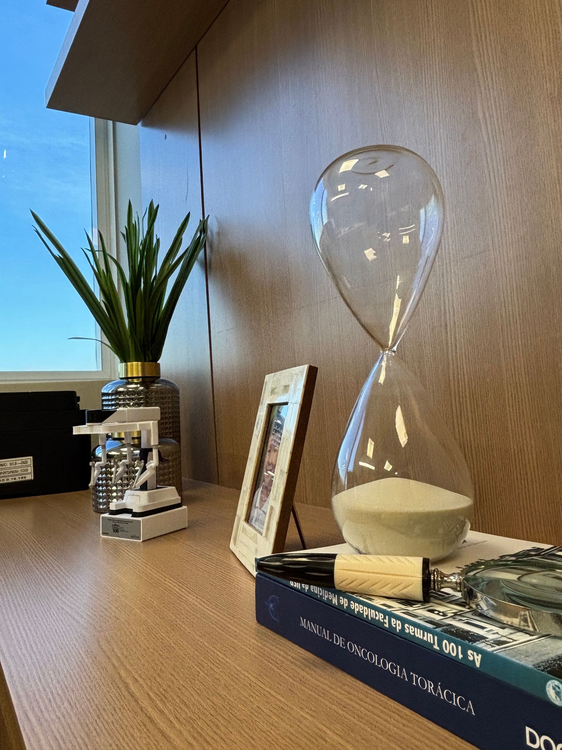 Uma ampulheta está em cima de uma pilha de livros sobre uma mesa.