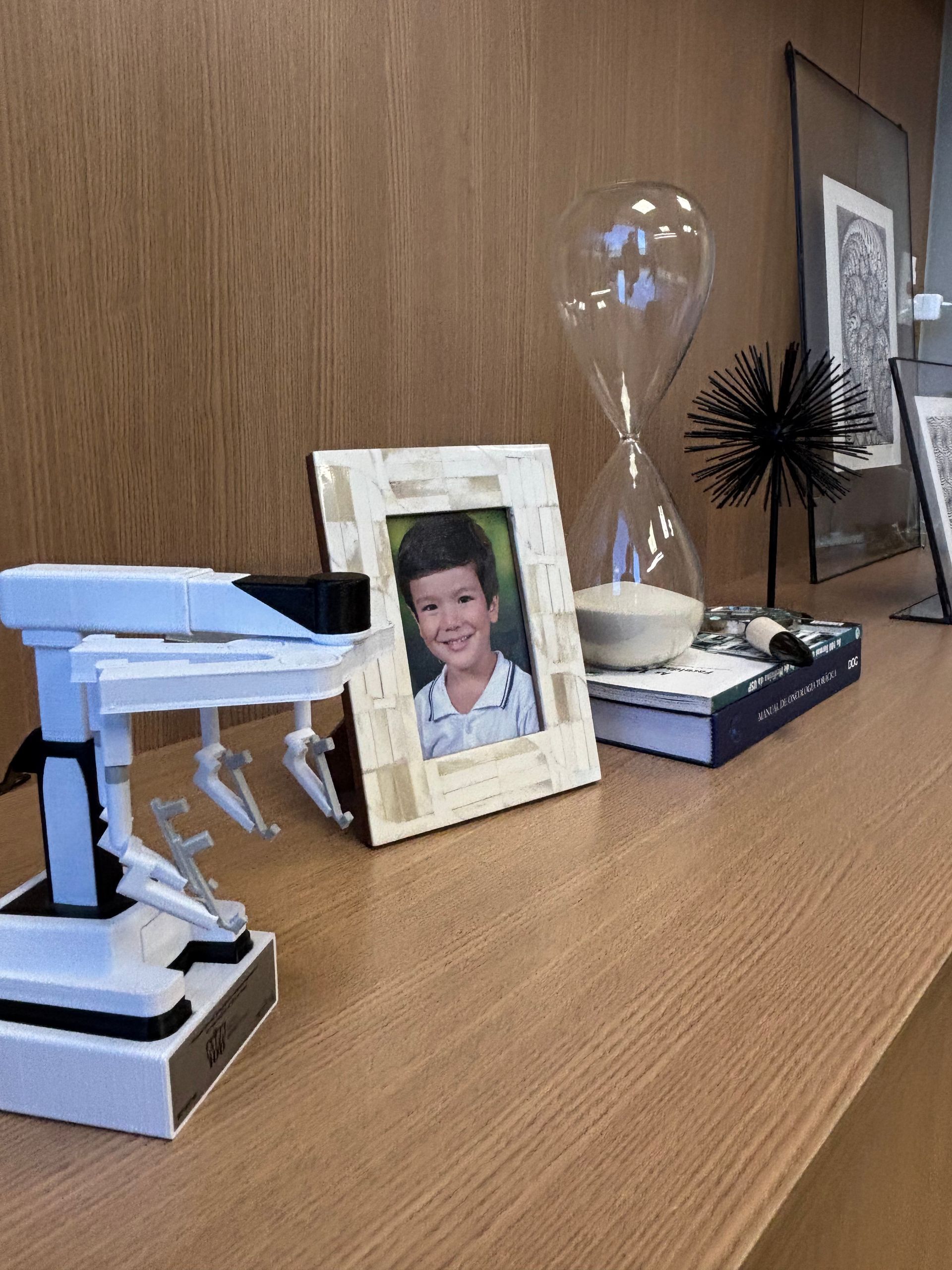 Uma moldura com a foto de um menino está sobre uma mesa de madeira.