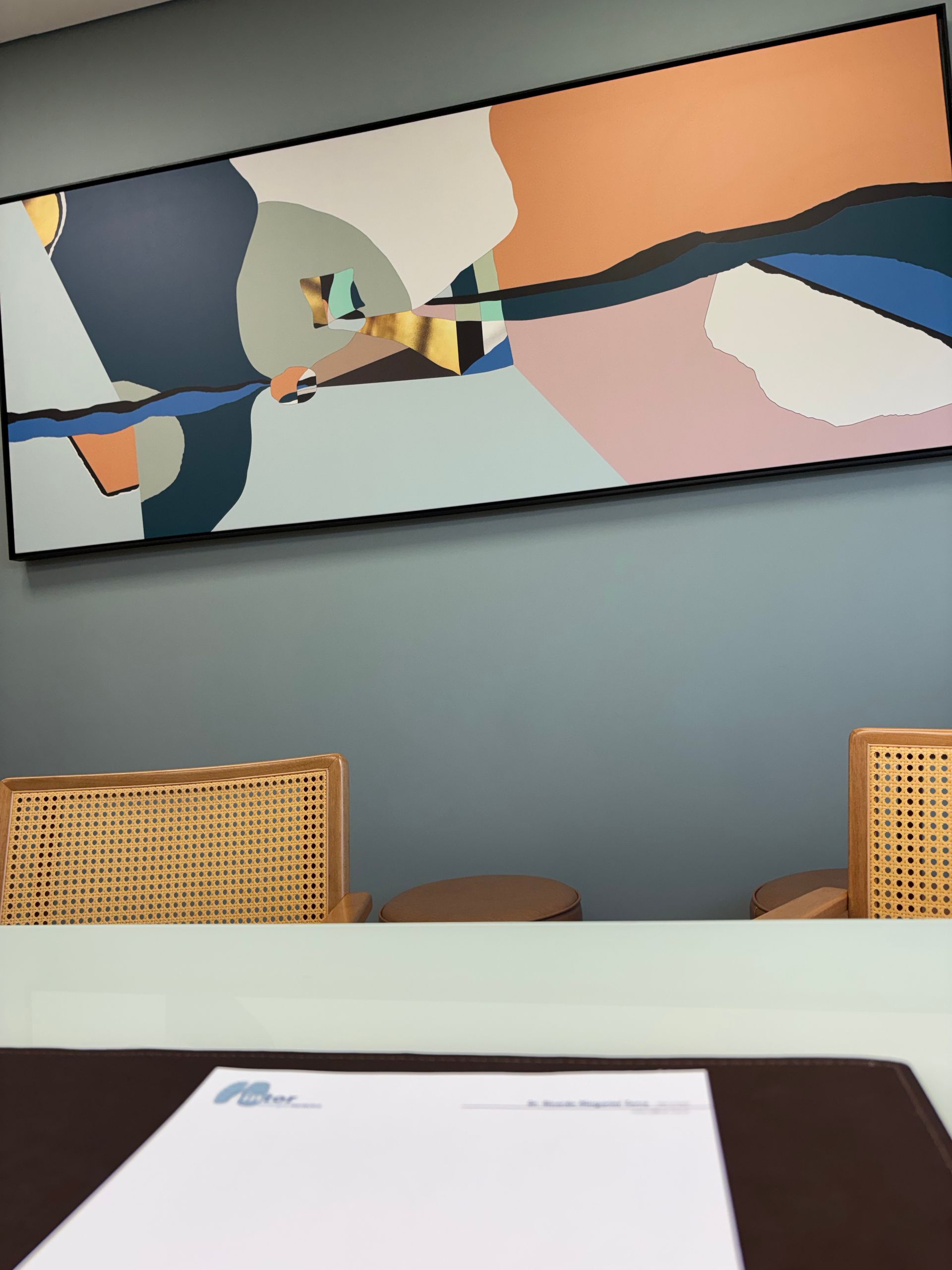 Uma grande pintura pendurada sobre uma mesa com papéis sobre ela