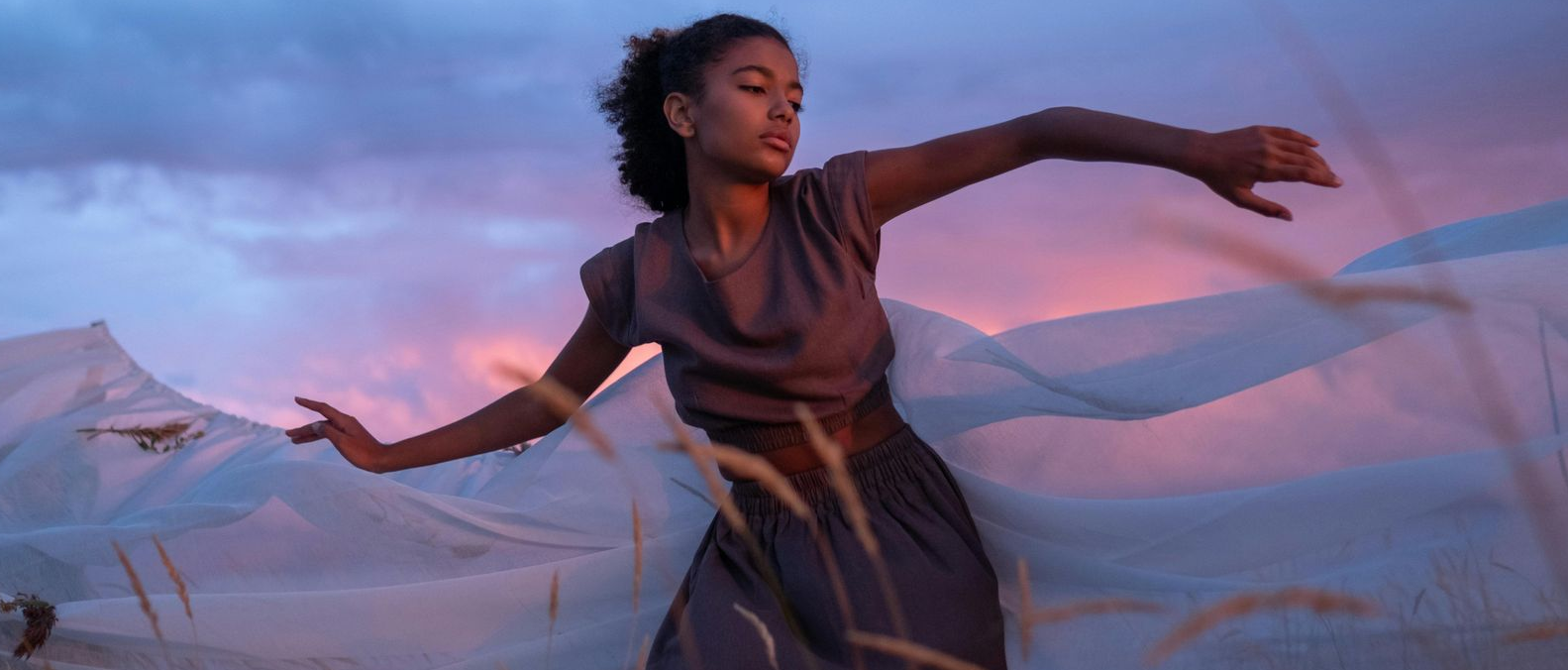 A woman is sitting in a chair talking to another woman who is laying on a couch.