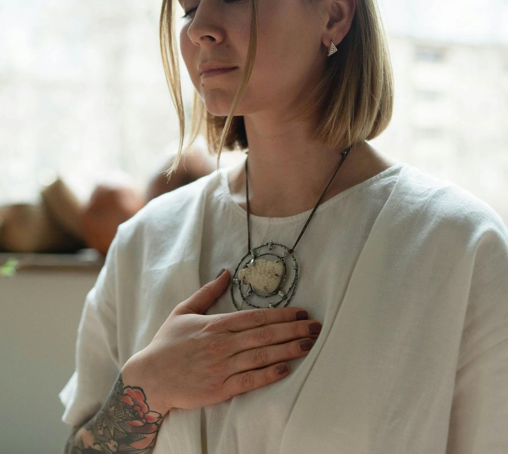 woman seated in the desert with  hands on heart and belly
