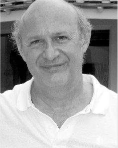 Uomo anziano sorridente con i capelli radi che indossa una polo bianca.