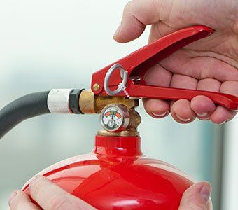 Hand Presses the Trigger of Fire Extinguisher - Fire Extinguisher Maintenance in Staten Island, NY