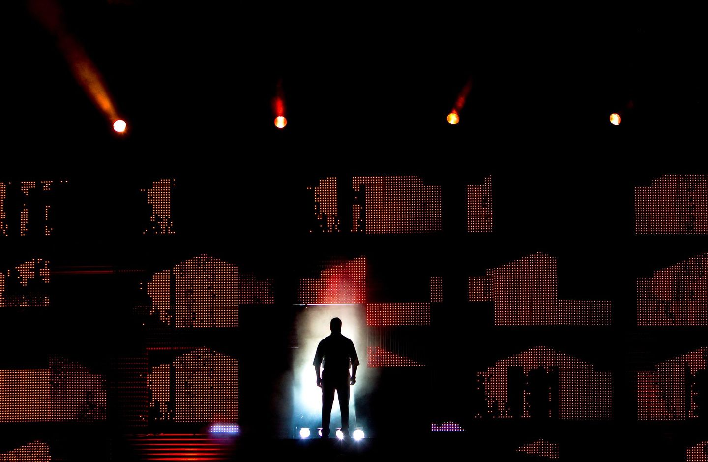 Man on stage  with dramatic lighting at corporate live event. The man is silhouetted. 