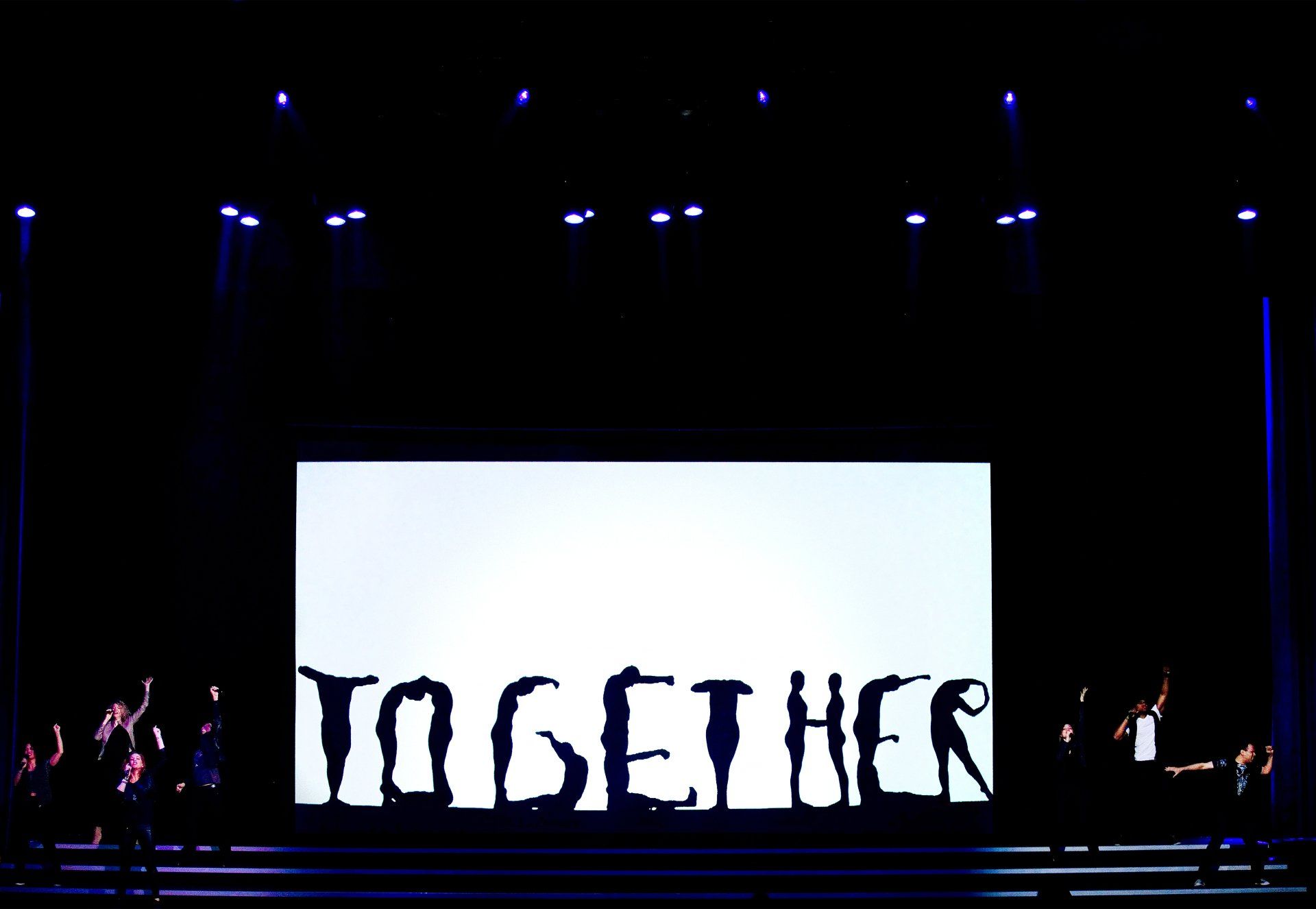 Dancers form the letters of the word together during a corporate event. 