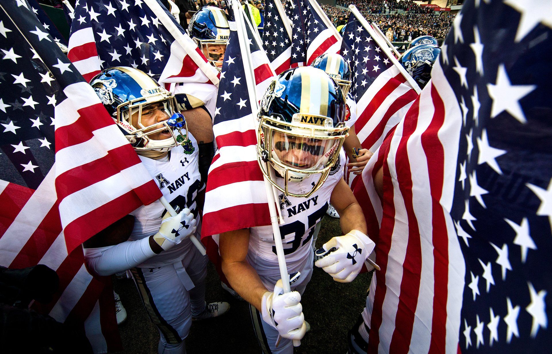 Navy football players carry American flags