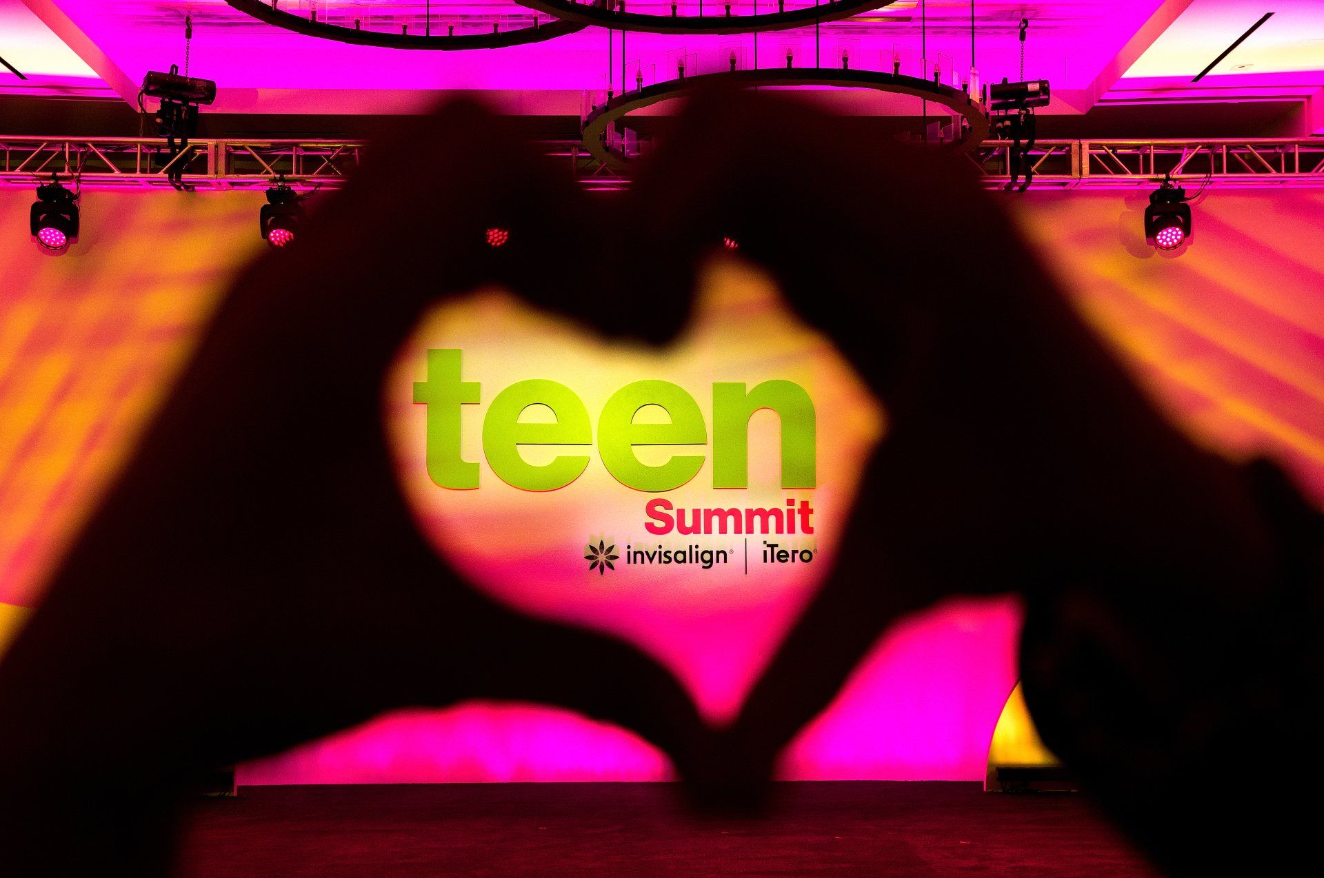 Hands form the shape of a heart at a teen summit. 