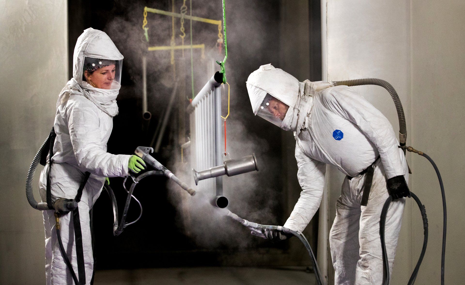 man and woman wearing safety suits while spraying  in a facility
