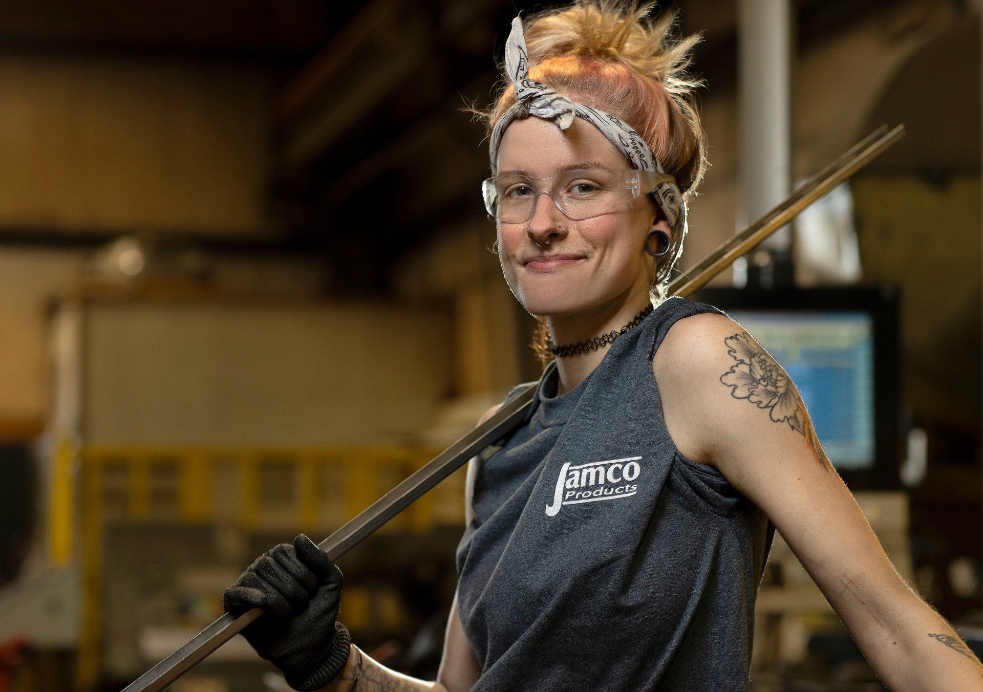 female employee at a manufacturing plant holding a rod 