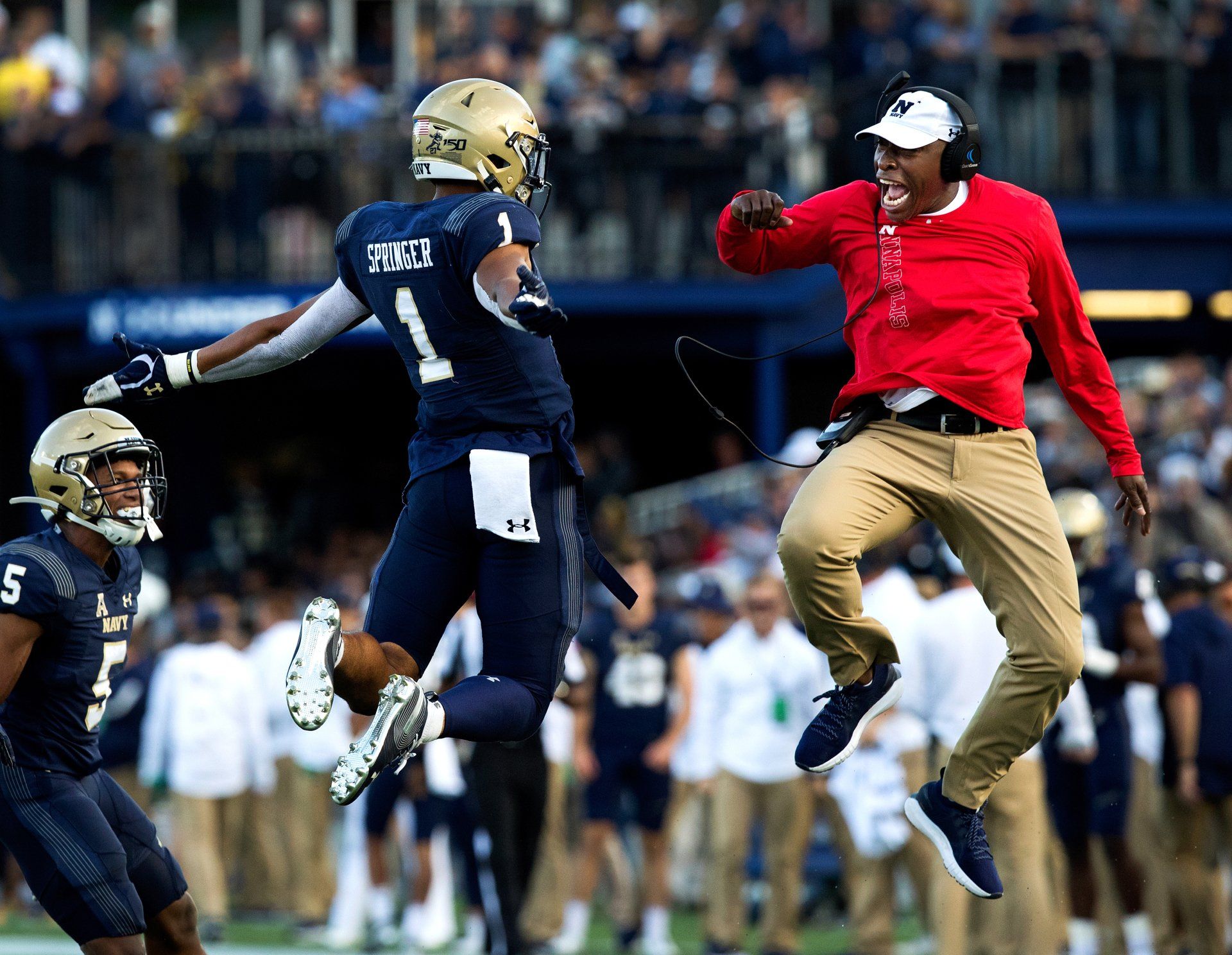 A football coach jump into the air to celebrate with a player